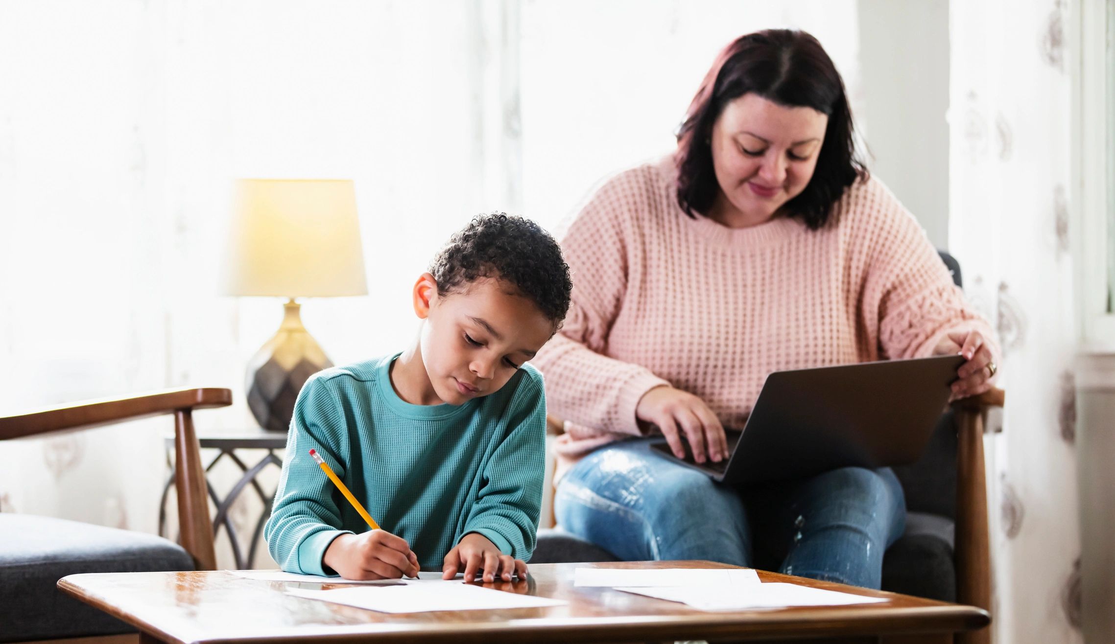 Parent working nearby while a child completes homework at home