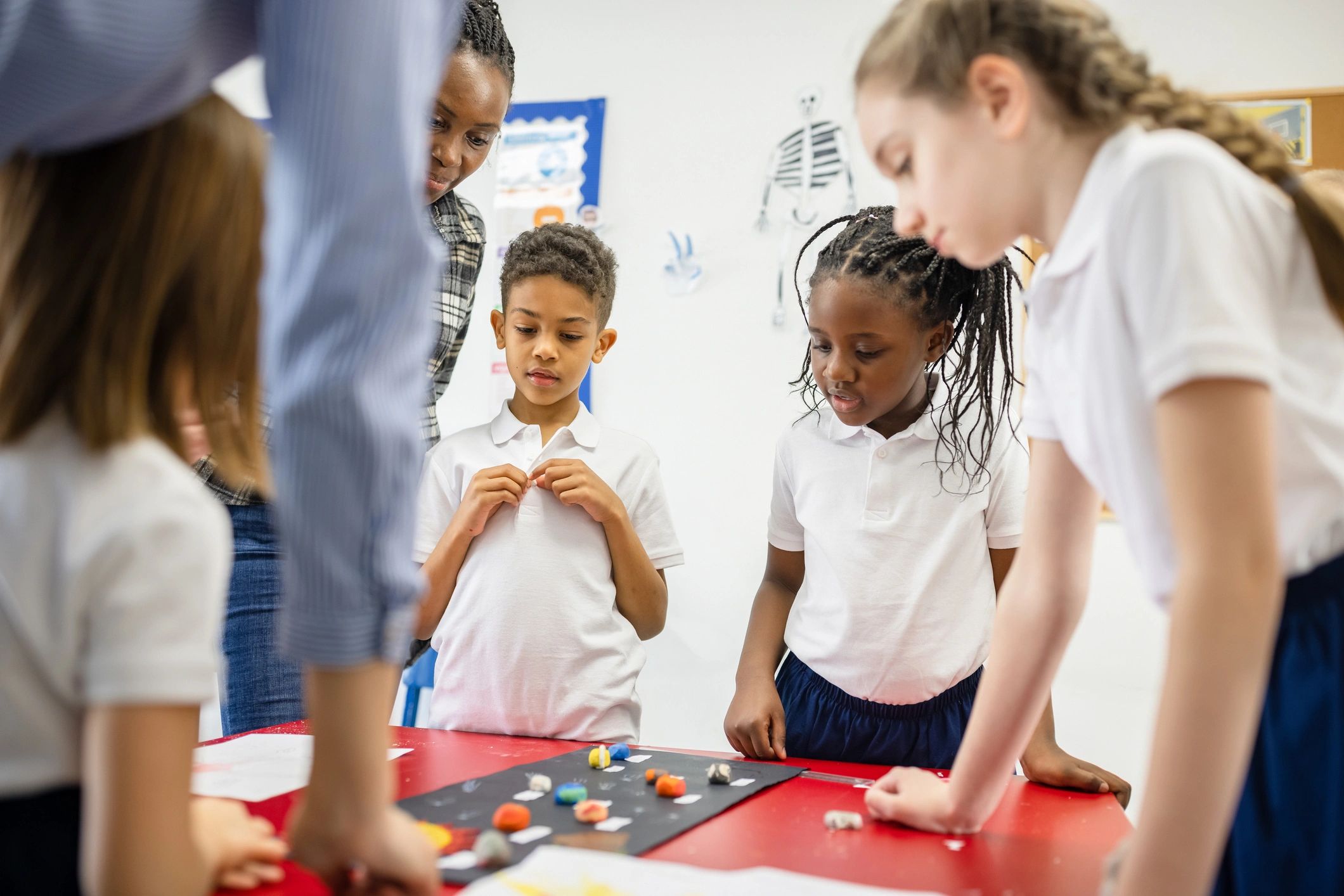 Teacher supporting children during an art activity in a classroom