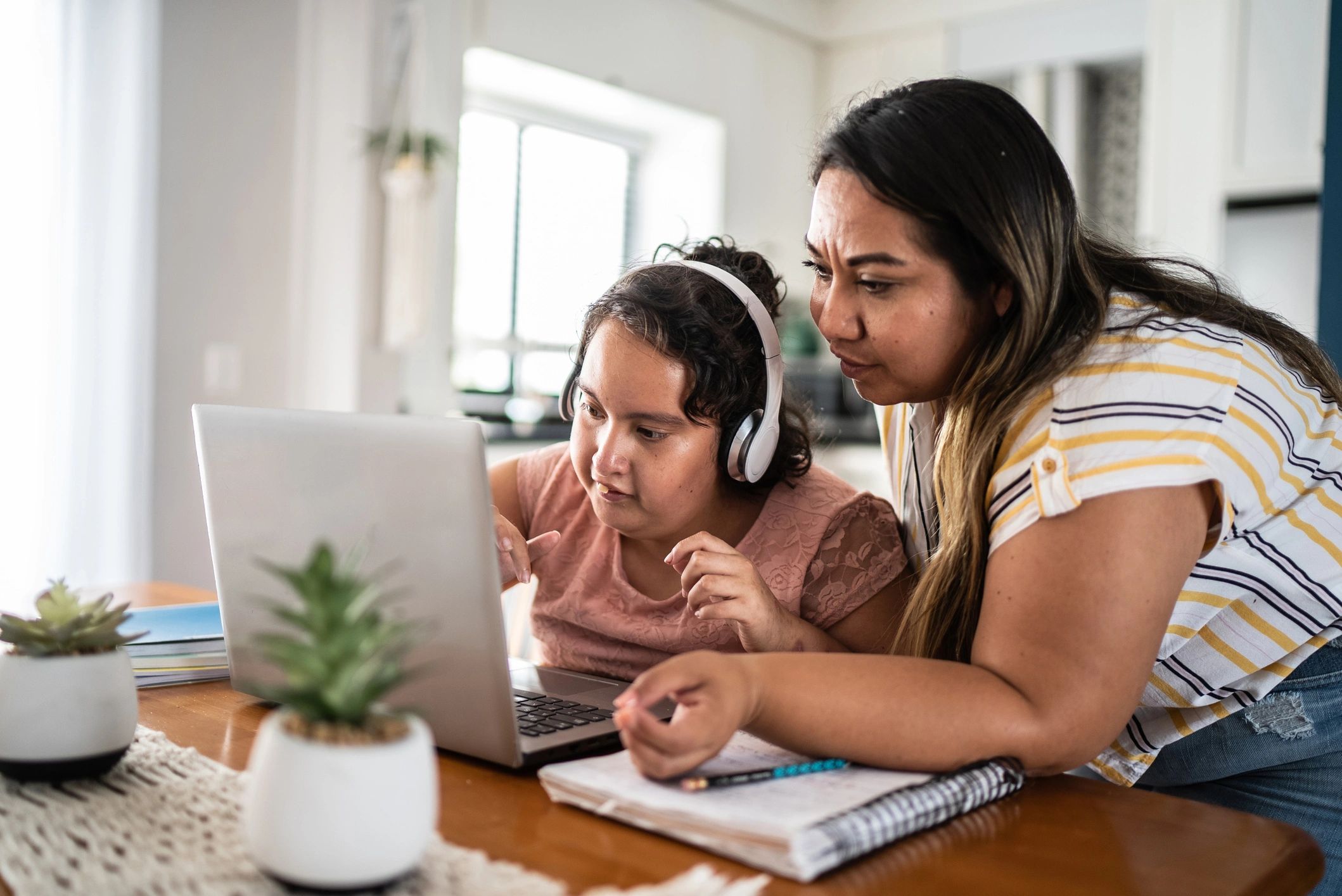 Parent supporting a child’s learning on a laptop at home