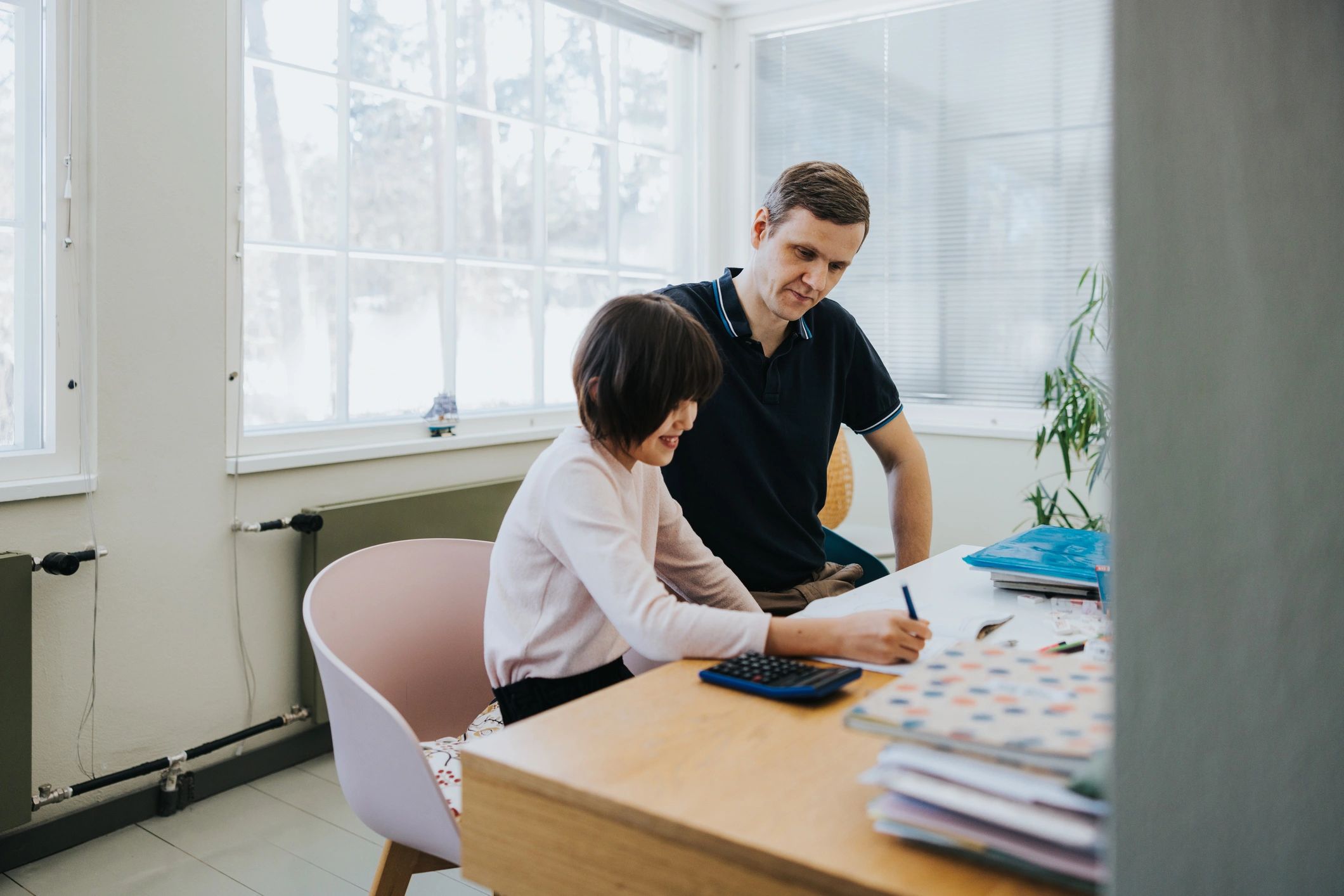 Parent helping a child with schoolwork at a table at home