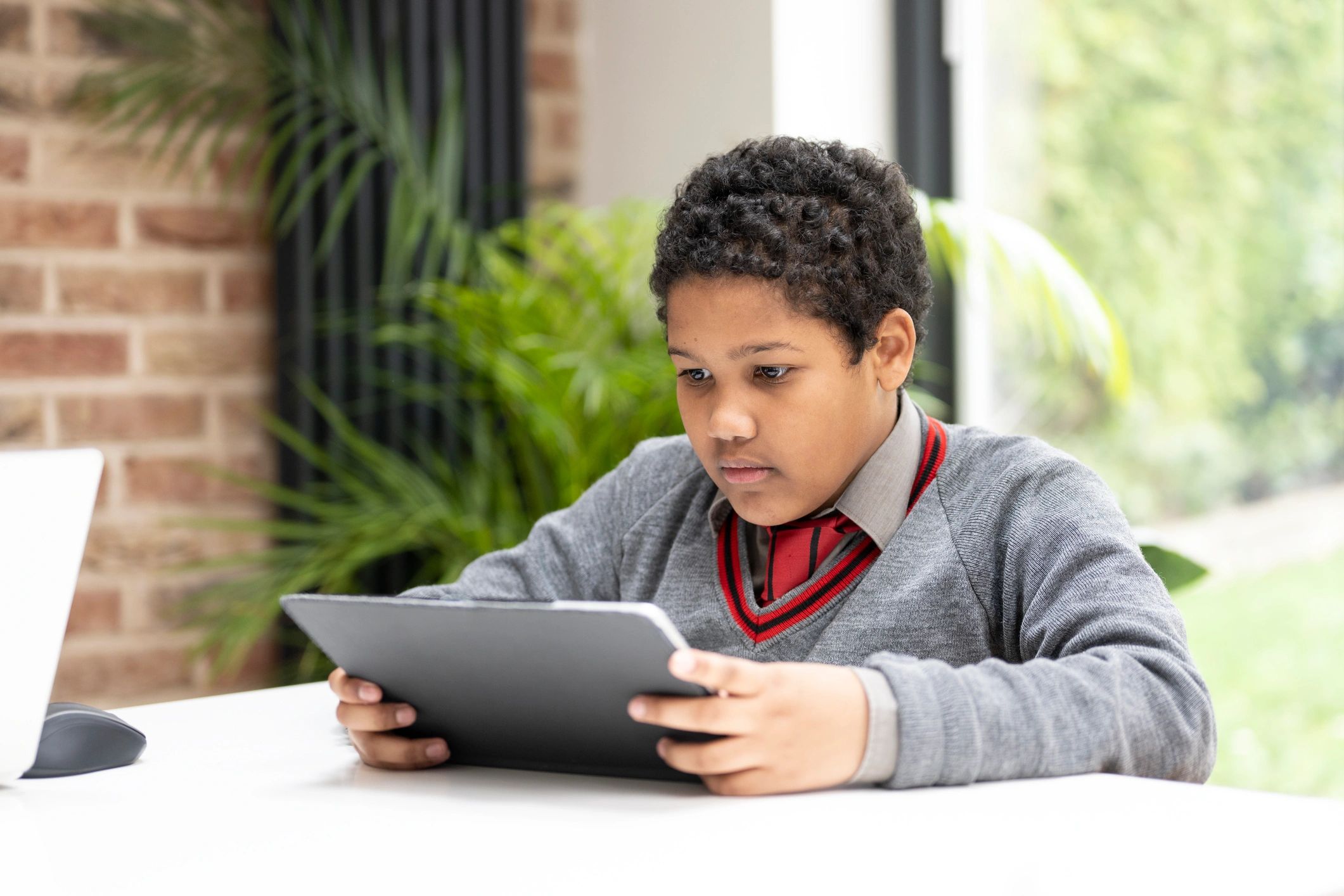 Child studying at home using a tablet at a table