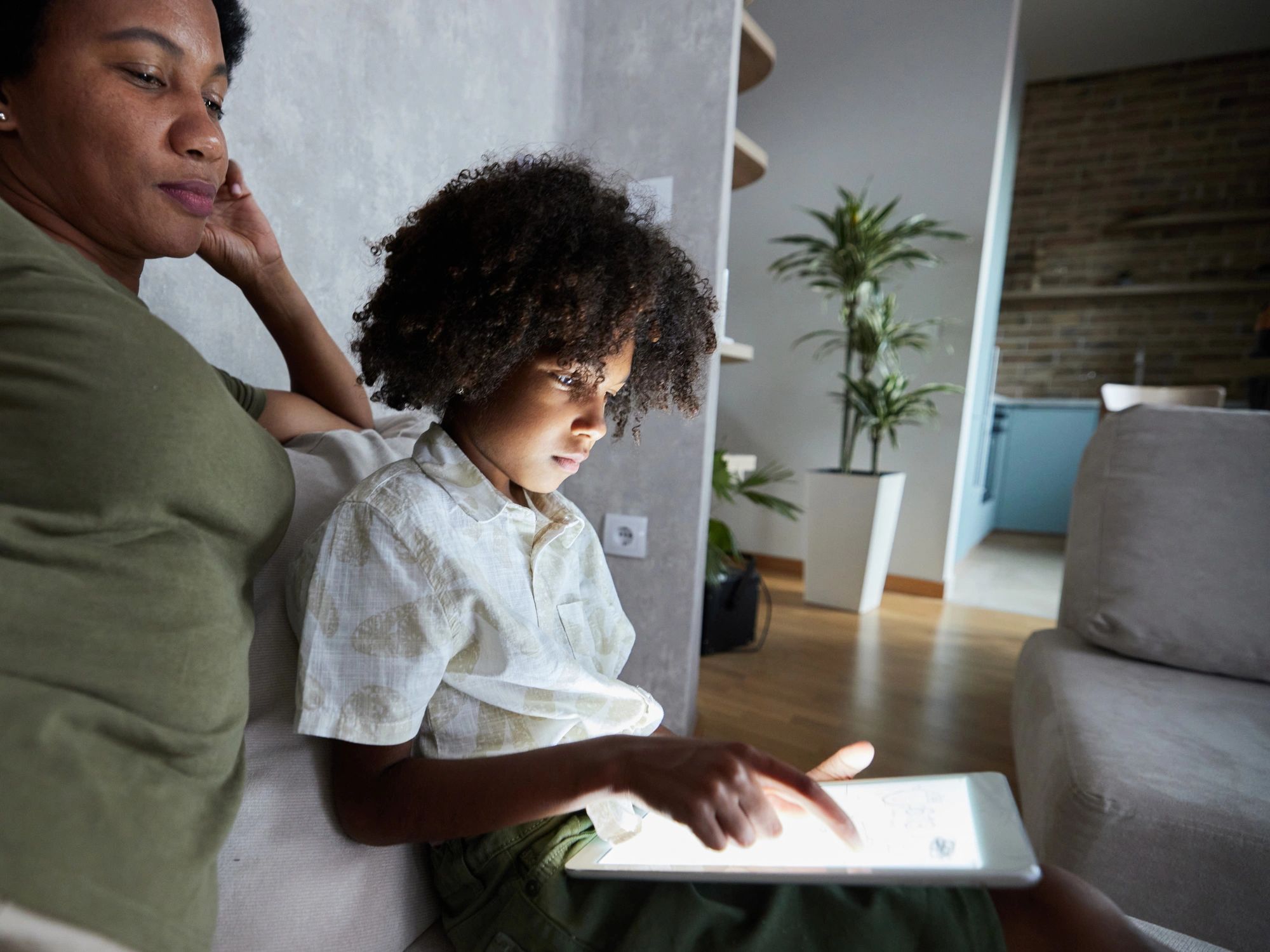 Parent supporting a child using a tablet at home for calm, self-paced learning