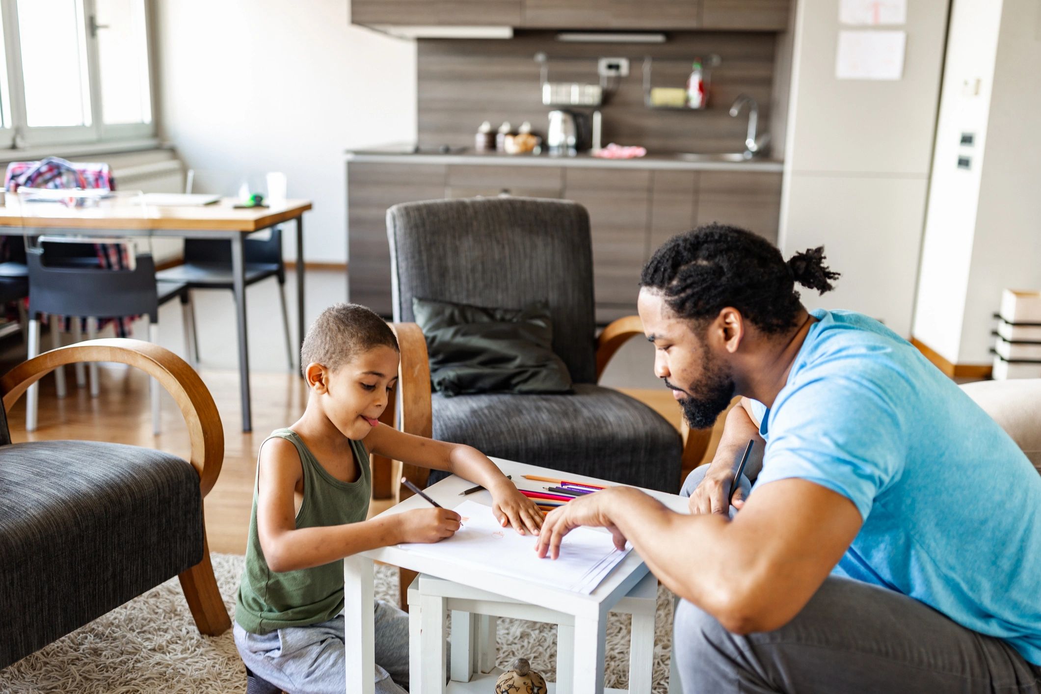 Father supporting his daughter with home learning at a table