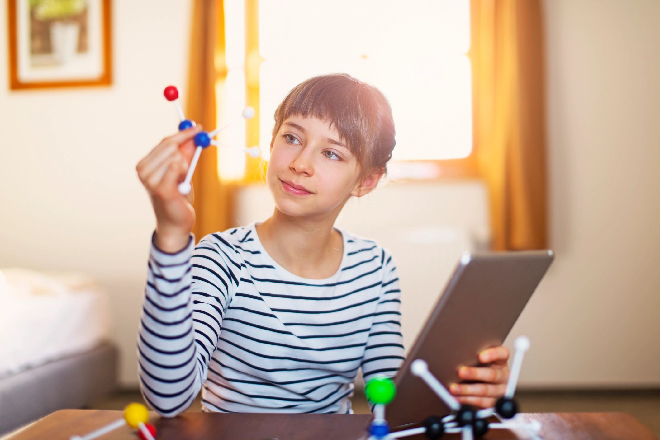 Child exploring science concepts with a tablet and learning models at a desk
